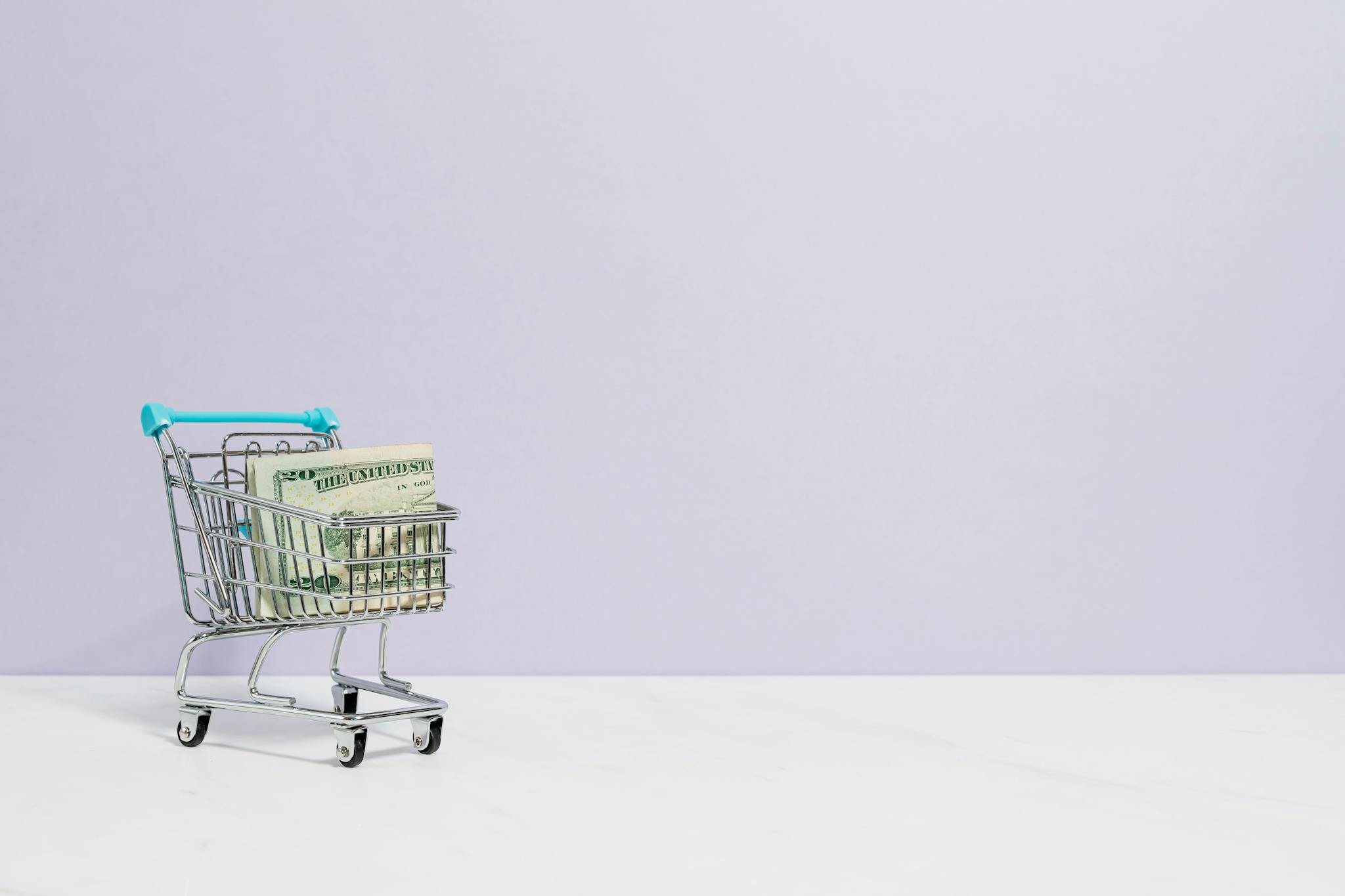 Shopping cart filled with cash on a plain background, ideal for finance and retail themes.